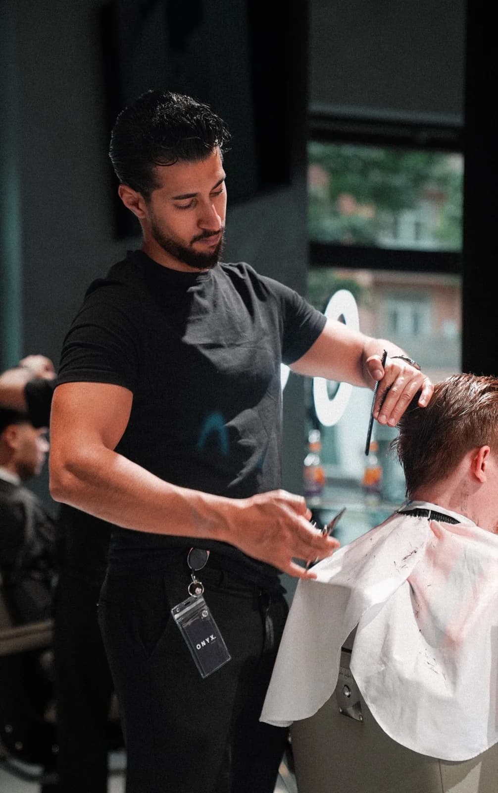 Barber von ONYX Cuts schneidet mit Schere und Kamm über Kamm — im Salon in der Nordbahnstraße in Wien.