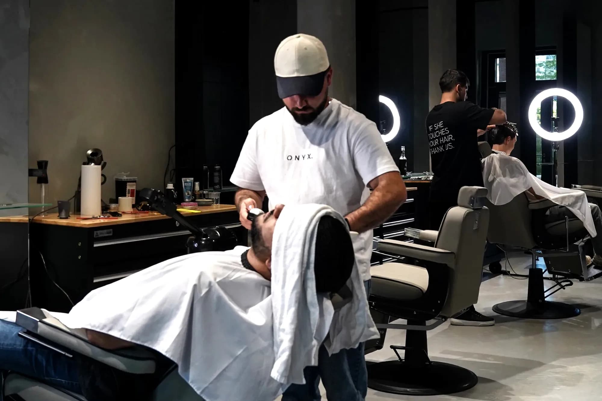Two barbers at work in ONYX Cuts in Vienna — the shop that is being franchised