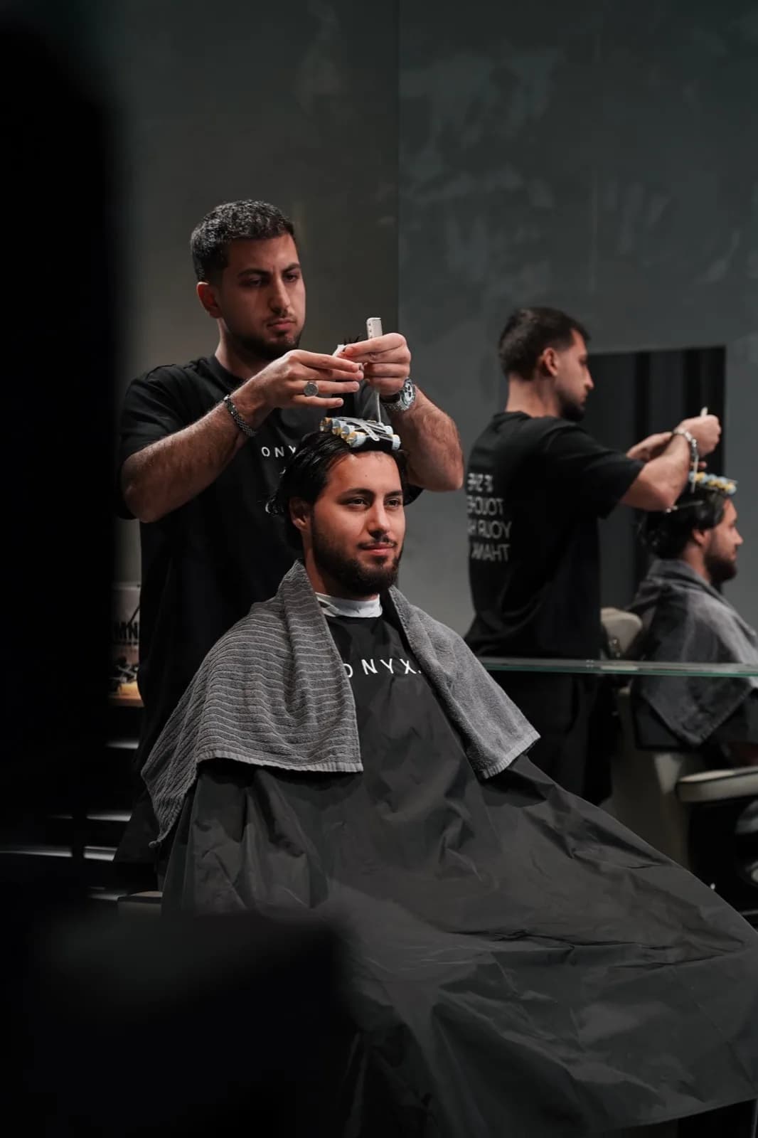Two barbers working at their chairs at ONYX Cuts in Vienna